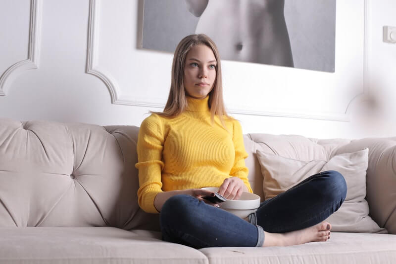 woman in a yellow sweater sitting on a couch